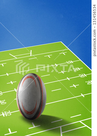 Contemporary collage. Oversized rugby ball on green marked field with blue sky 131456534