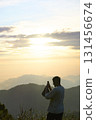Person capturing sunrise mountain view using smartphone 131456674
