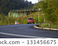 Red suv driving on winding asphalt road uphill 131456675