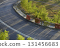 Asphalt road curving with shadows and plastic barriers 131456683