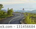 Winding mountain road disappearing into morning fog 131456684