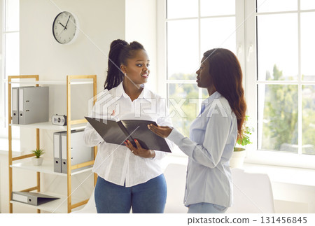Two young African American women with corporate business documents in the office 131456845