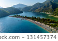 Aerial drone view of the Blue Lagoon in Oludeniz, Fethiye, Turkey with turquoise water, sandy beach, sunbeds, umbrellas and green mountains in summer. 131457374