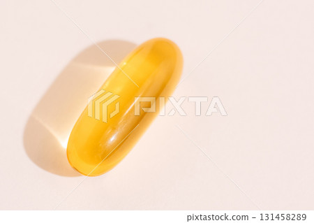 Yellow softgel vitamin macro with hard light shadow on pastel background minimal wellness concept Yellow softgel vitamin macro with hard light shadow on pastel background minimal wellness concept 131458289