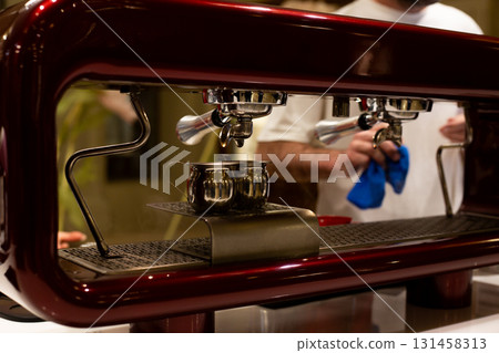 Close up shot of professional espresso machine brewing coffee. The rich, dark liquid flows from the spout, captured with steam rising, highlighting the precision of the coffee making process 131458313