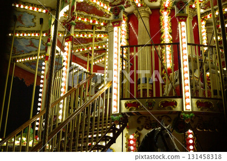 Carousel at night, with vintage style decorations and glowing lights illuminating structure. Nostalgic and joyful atmosphere of fairground ride, evoking sense of childhood wonder and excitement 131458318
