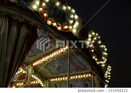 Close up of vintage carousel illuminated with bright lights, creating nostalgic, festive atmosphere. The colorful lights and details highlight the magic and fun of the fairground at night Close up of vintage carousel illuminated with bright lights, creating nostalgic, festive atmosphere. The colorful lights and details highlight the magic and fun of the fairground at night 131458322