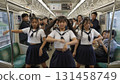 A synchronized photo of three Asian women in sailor uniforms posing with the Yamanote Line in the background 131458749