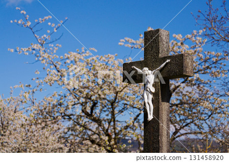 Beautiful Jesus Christ on crucifix, cemetery on a sunny day, spring, Easter, new life and religion concept Beautiful Jesus Christ on crucifix, cemetery on a sunny day, spring, Easter, new life and religion concept 131458920