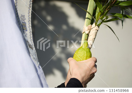 Succot. Jewish man in a Tallit praying while waving the Four Species, Lulav and Etrog Succot. Jewish man in a Tallit praying while waving the Four Species, Lulav and Etrog 131458966