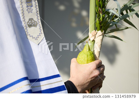 Succot. Jewish man in a Tallit praying while waving the Four Species, Lulav and Etrog Succot. Jewish man in a Tallit praying while waving the Four Species, Lulav and Etrog 131458979