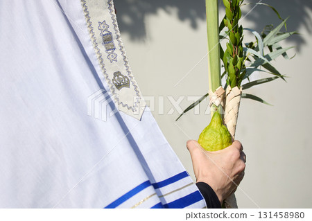 Succot. Jewish man in a Tallit praying while waving the Four Species, Lulav and Etrog Succot. Jewish man in a Tallit praying while waving the Four Species, Lulav and Etrog 131458980