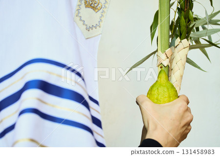 Succot. Jewish man in a Tallit praying while waving the Four Species, Lulav and Etrog Succot. Jewish man in a Tallit praying while waving the Four Species, Lulav and Etrog 131458983