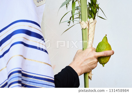 Succot. Jewish man in a Tallit praying while waving the Four Species, Lulav and Etrog Succot. Jewish man in a Tallit praying while waving the Four Species, Lulav and Etrog 131458984