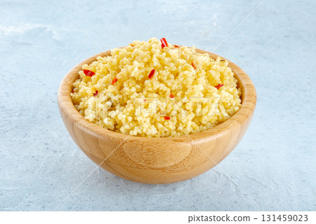Cooked millet, ancient African grain, in a wooden bowl on a blue background 131459023