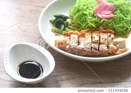Chinese jade noodles topping roasted crispy pork and cabbage with pnk pickled ginger dipping sweet soy sauce on plate  131459098