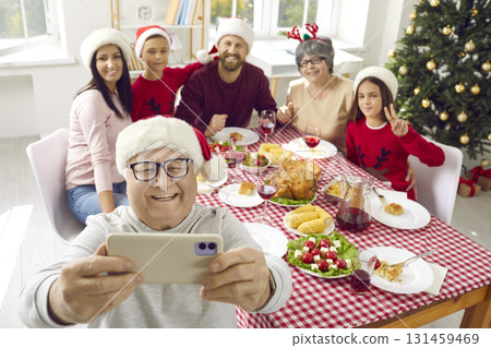 Happy grandpa taking family selfie on mobile phone during Christmas dinner at home 131459469