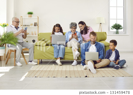Big family sitting in living room with gadgets, parents, grandparents and two children. 131459478