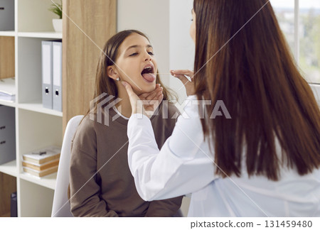 Doctor otolaryngologist examining little girl patient's throat in medical clinic. 131459480