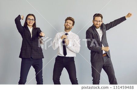 Three business people dancing and celebrate success in business isolated on grey background. 131459488