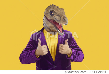 Portrait of happy, positive man in purple suit and funny dinosaur mask giving thumbs up 131459491