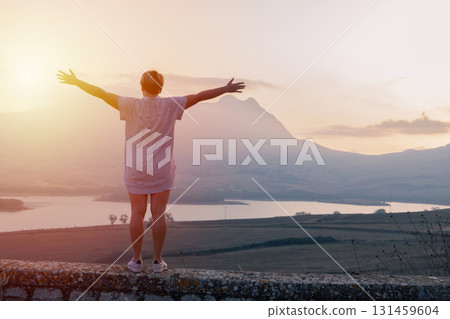 Sunrise travel moment, arms raised above mountain valley and calm lake landscape 131459604