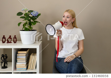 Woman shouting into megaphone while sitting indoors Woman shouting into megaphone while sitting indoors 131460038