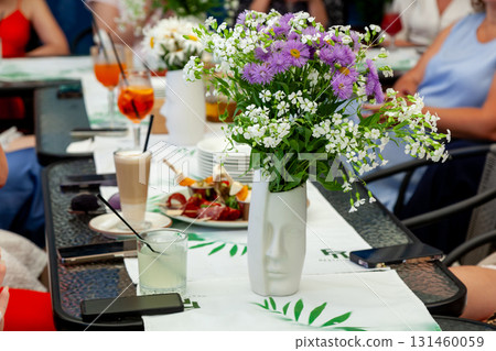 Elegant table setting with floral centerpiece at outdoor brunch 131460059