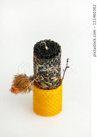 Natural hand-rolled beeswax candle with herbs on a light background Natural hand-rolled beeswax candle with herbs on a light background 131460362