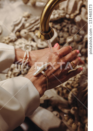 Young woman cleans her hands by elegant washbasin decorated with seashells and unique pearl beads 131460373