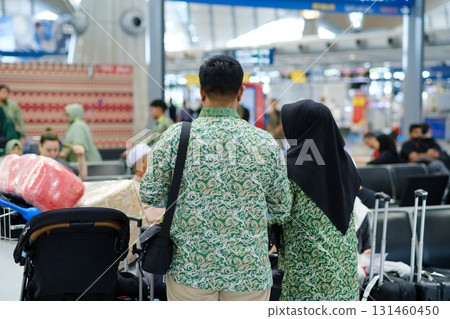 Travelers in matching green outfits prepare for departure at the airport with luggage and family in the background during peak travel hours Travelers in matching green outfits prepare for departure at the airport with luggage and family in the background during peak travel hours 131460450