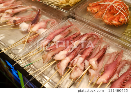 Grilled octopus skewers displayed at a lively night market in an Asian city during a bustling evening street food event Grilled octopus skewers displayed at a lively night market in an Asian city during a bustling evening street food event 131460455