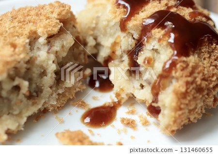 A fluffy Hokkaido potato croquette cut in half and topped with sauce 131460655