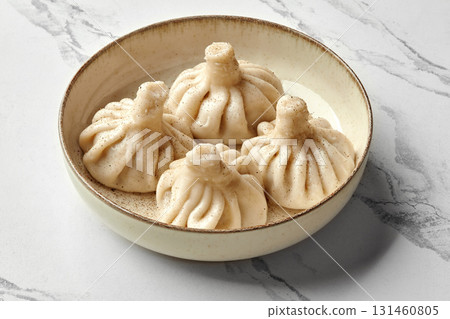 Delicious khinkali dumplings served on a plate, sprinkled with black pepper 131460805