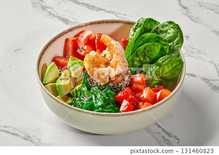 Poke bowl with salmon, shrimp, chuka seaweed, tomatoes, avocado, and spinach leaves 131460823