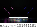 Brightly lit circular stage podium on a dark background with vibrant iridescent light reflections on the floor, glowing pink blue wavy lines floating above. Ideal for product display or event. 131461161