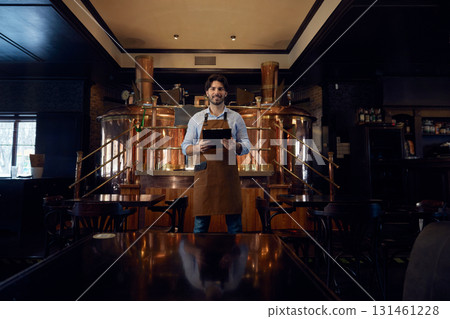 Brewer man dressed in an apron is standing in brewery 131461228