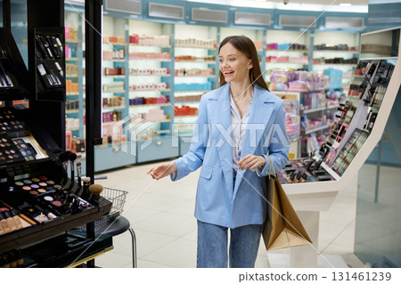 A woman wearing a stylish blue jacket is shopping in a cosmetics store 131461239