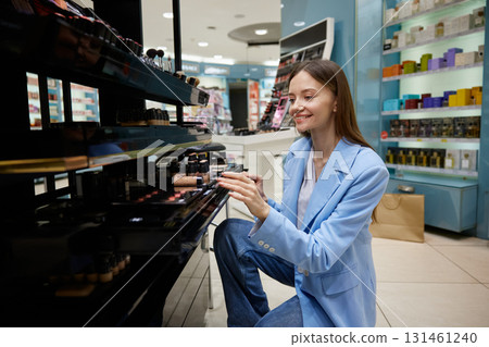 A woman in a blue jacket is browsing makeup items in a store A woman in a blue jacket is browsing makeup items in a store 131461240