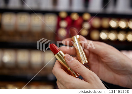 A woman is gracefully holding a bright red lipstick in her hand A woman is gracefully holding a bright red lipstick in her hand 131461368