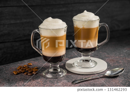 Layered coffee latte drinks. Hot coffee drinks in glass mugs, dark background Layered coffee latte drinks. Hot coffee drinks in glass mugs, dark background 131462293