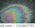 Oil slick creating iridescent rainbow colors on asphalt pavement 131462795