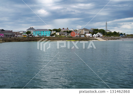 Coastal town in Ireland with colorful buildings against a cloudy sky, viewed across the water. Coastal town in Ireland with colorful buildings against a cloudy sky, viewed across the water. 131462868