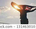 Celebrating American Freedom. Patriotic Man Holding Flag Against the Sun 131463010
