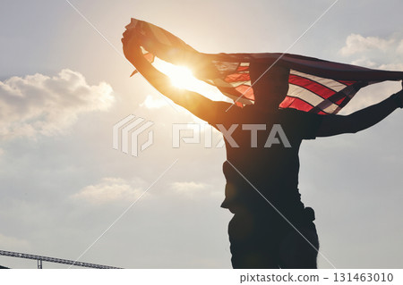 Celebrating American Freedom. Patriotic Man Holding Flag Against the Sun Celebrating American Freedom. Patriotic Man Holding Flag Against the Sun 131463010