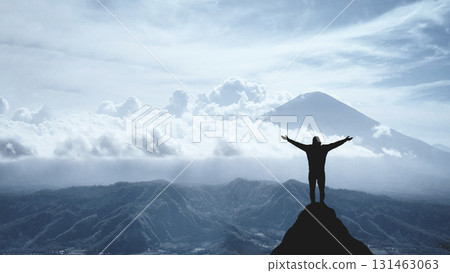 Silhouette of a jubilant man on the peak of a mountain, concept of victory and achievement 131463063