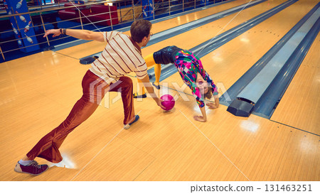 Man and woman performing playful acrobatics on bowling lane with retro outfits Man and woman performing playful acrobatics on bowling lane with retro outfits 131463251