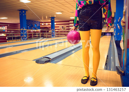Woman in retro bowling fashion with pink ball on lane 131463257
