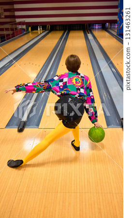Woman in colorful patterned shirt and yellow tights bowling with green ball Woman in colorful patterned shirt and yellow tights bowling with green ball 131463261