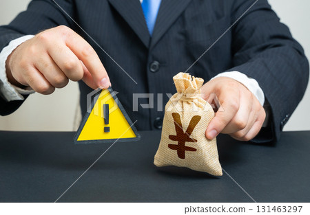 A man with a sign of attention and a yen or yuan money bag. Restrictions, monetary policy. Sanctions, budget deficit, emergency fund. Useful for finance, banking, trade, economy and risk management. A man with a sign of attention and a yen or yuan money bag. Restrictions, monetary policy. Sanctions, budget deficit, emergency fund. Useful for finance, banking, trade, economy and risk management. 131463297
